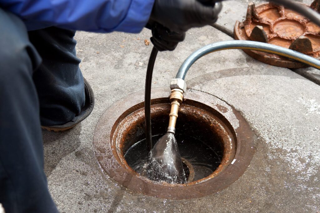 Plumber hydro jetting a sewer line through a manhole in Apopka