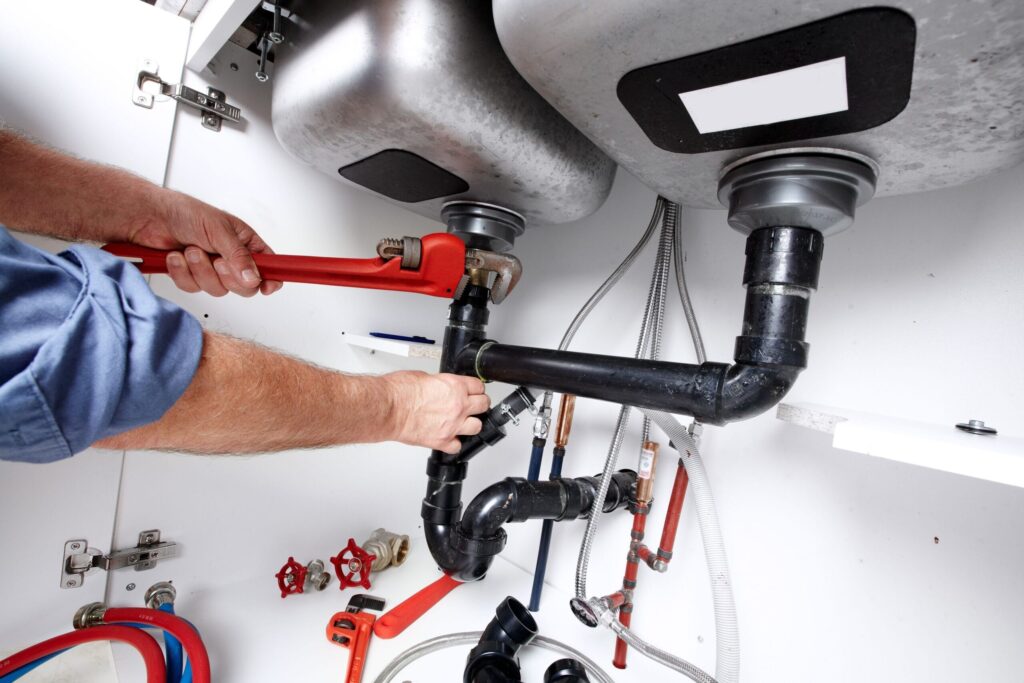 Plumber repairing drain pipes beneath a kitchen sink in Apopka