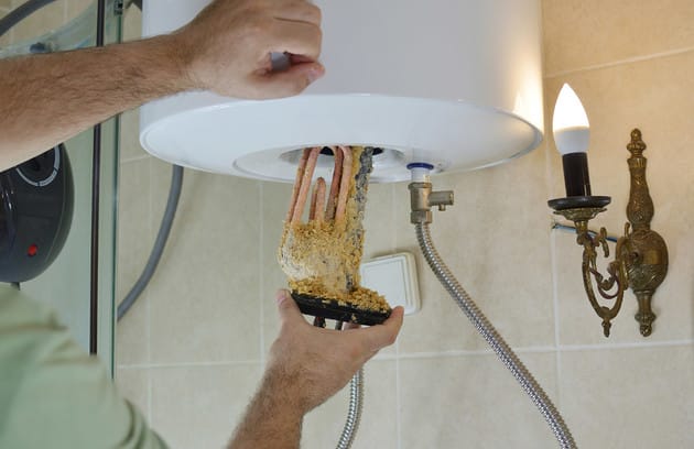 Technician removing mineral buildup from a water heater in Apopka
